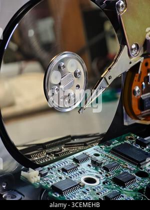Open hard disk drive revealing internal components, including platter, read/write head, and circuit board Stock Photo