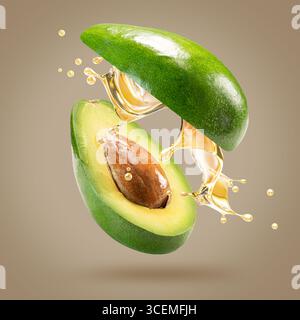 avocado with oil splash on a light brown background. Stock Photo