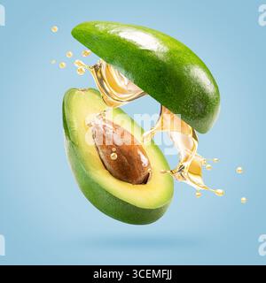 avocado with oil splash on a light blue background. Stock Photo