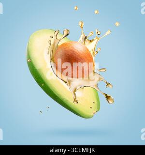 avocado with oil splash on a light blue background. Stock Photo