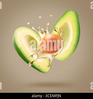 avocado with oil splash on a light brown background. Stock Photo