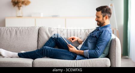 Relaxed bearded man using digital tablet at home Stock Photo