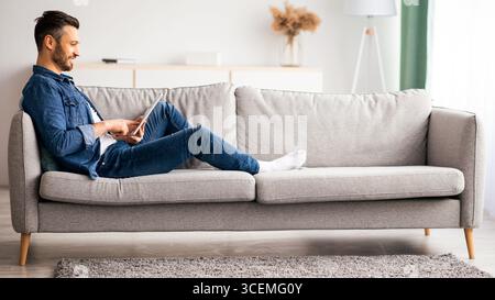Handsome bearded man using digital tablet at home Stock Photo