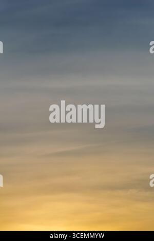 The blue and golden colors of the sky during sunset (golden hour). Colorful abstract landscape formed by clouds and sunlight in the late afternoon. Stock Photo