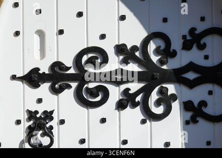 Ornate Iron Details on White Wooden Door with Traditional Design. Adderbury, England Stock Photo