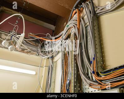 Electric cables in protective flexible corrugated sleeves routed through cable ducts mounted on walls. Stock Photo