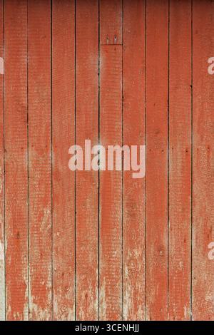 Textured red wooden wall displays wear and natural patterns, reflecting years of use in a quiet countryside environment. Stock Photo