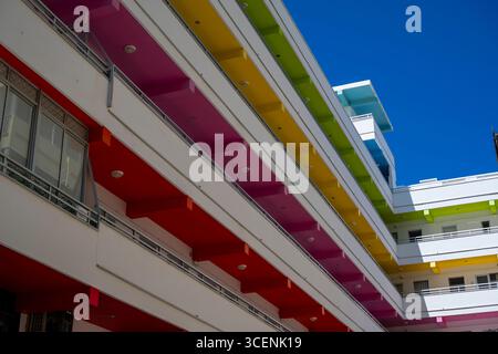 A building with a colorful facade and a blue sky in the background. The building has a rainbow-colored design and is located in a city Stock Photo