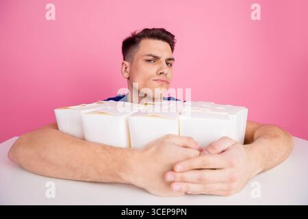 Handsome man with food containers poses confidently against a pink background for casual and stylish lifestyle themes Stock Photo