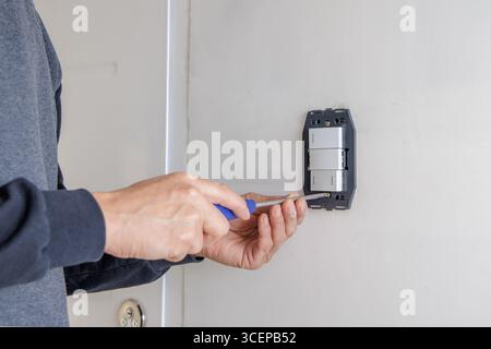 Hands of an electrician installing an electrical switch. Stock Photo