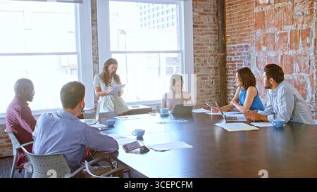 Businesswoman Leading Meeting With Colleagues In Boardroom Stock Photo