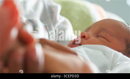 Close Up Of Mother Holding Sleeping Newborn Baby In Nursery At Home Stock Photo