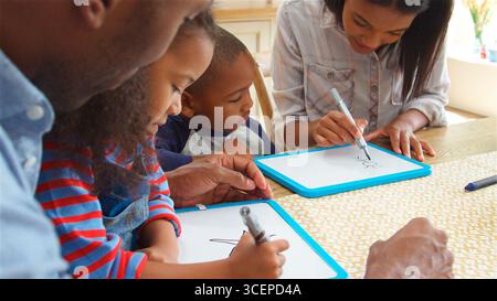 Parents And Children Drawing On Whiteboards Sitting Around Table At Table Stock Photo