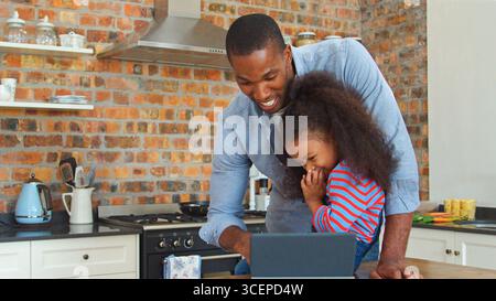 Father And Daughter Using Digital Tablet In Kitchen At Home Stock Photo