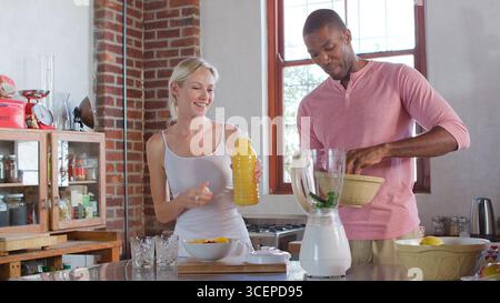 Young Couple Wearing Pajamas At Home Making Healthy Breakfast Drink With Fresh Fruit Stock Photo