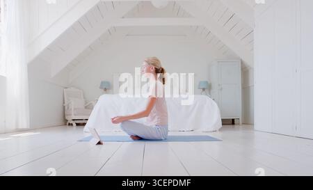 Woman With Digital Tablet Sitting In Bedroom Doing Yoga Stock Photo