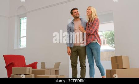 Excited Young Couple Looking Around New Home On Moving Day Together Stock Photo