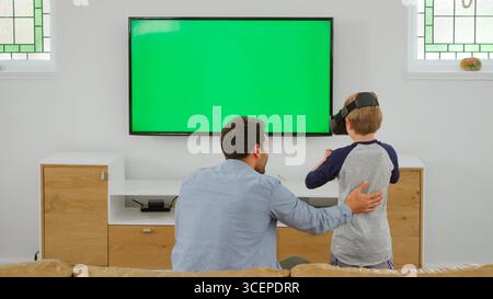 Father And Son Play Computer Game Using Virtual Reality Headset Stock Photo