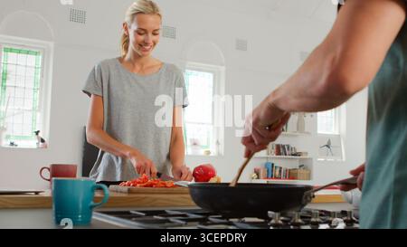 Close Up Of Young Couple Preparing Meal Together In Modern Kitchen Stock Photo