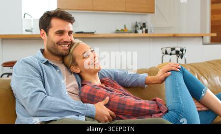 Young Couple Sitting On Couch At Home Watching Television Together Stock Photo