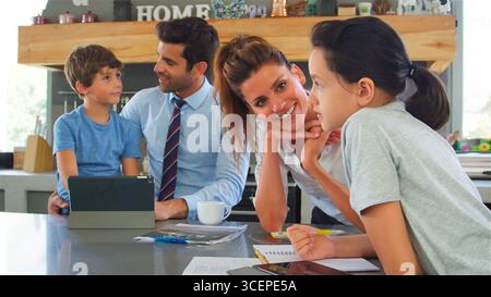 Parents Helping Children With Homework Using Digital Tablet Before Going To Work Stock Photo