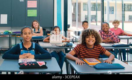Portrait Of Smiling High School Class Using Digital Tablets In Class Stock Photo