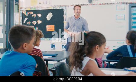 Male High School Teacher Standing In Front Of Multi-Cultural Class Stock Photo