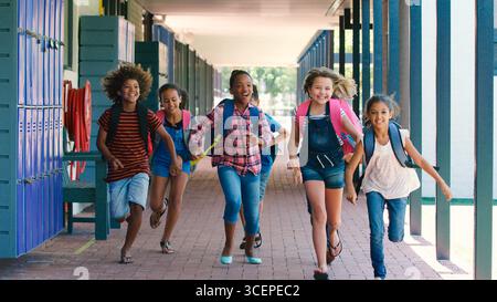 Portrait Of High School Students Wearing Backpacks Outside School Building Running Towards Camera Stock Photo