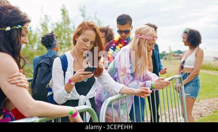 Young People At Outdoor Music Festival Using Mobile Phone To Arrange Meeting Stock Photo