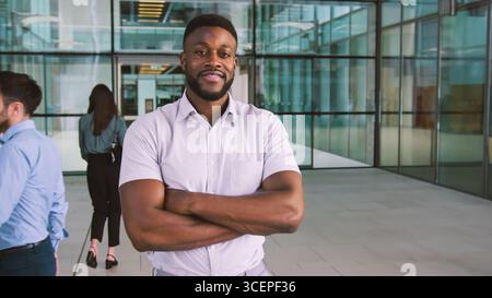 Portrait Of Smiling Businessman Standing In Lobby Of Busy Modern Office Stock Photo