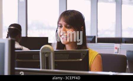 Young Businesswoman Wearing Telephone Headset Working In Customer Services Department Stock Photo