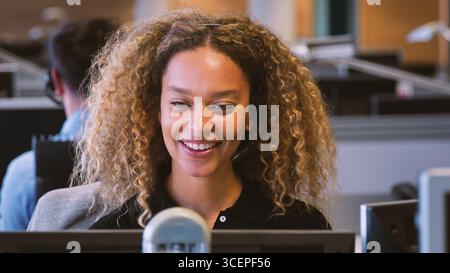 Young Businesswoman Wearing Telephone Headset Working In Customer Services Department Stock Photo