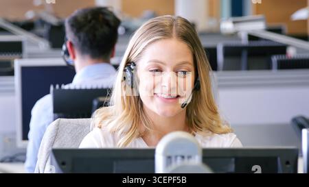 Businesswoman Wearing Telephone Headset Working In Customer Services Department Stock Photo