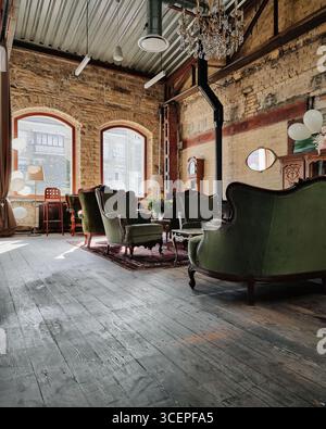 Interior of the old house with brick walls, green armchairs and hardwood floor. Stock Photo
