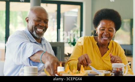 Senior Couple At Home Enjoying Breakfast Around Table Together Stock Photo