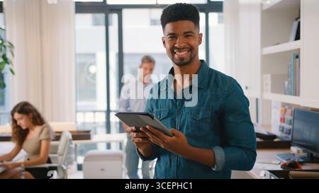 Young Smiling Businessman With Digital Tablet Standing And Working In Modern Office Stock Photo