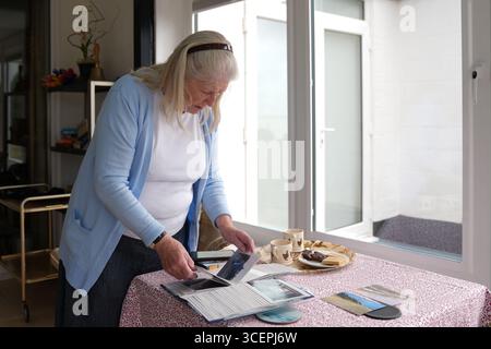88-year-old Jean Flick looking through family photos at her home in North End Avenue, Thorpeness, Suffolk, which is at risk of falling into the sea following coastal erosion. Mrs Flick has been told that once the cliff edge is within five metres of her house, she will have to demolish the nearly 100-year-old building. Picture date: Tuesday August 19, 2025. Stock Photo