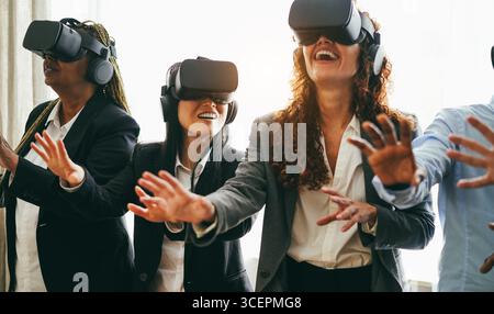 Business people wearing vr goggles inside office - New technology and ai concept - Main focus on left asian girl face Stock Photo