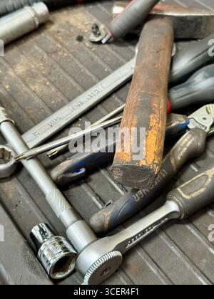 Assorted mechanic tools including hammer, wrenches, and screwdrivers in a car workshop. Stock Photo
