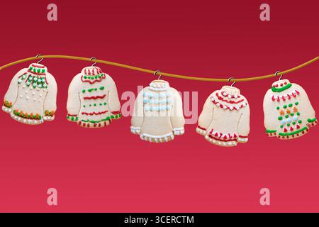 Ugly sweater Christmas cookies hanging on golden rope on red background Stock Photo