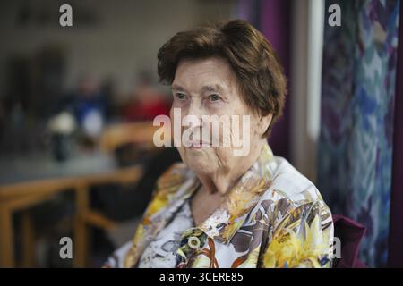 An elderly woman over 90 years old looks thoughtfully sitting in a cafeteria in a retirement home, Cologne, North Rhine-Westphalia, Germany Stock Photo