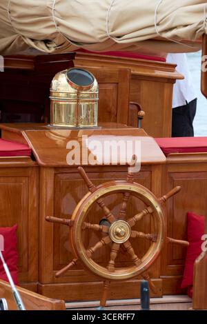 Close-Up of a Wooden Ship Wheel and Nautical Compass on Deck Stock Photo