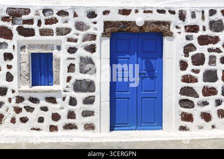 Bright blue door and blue shutter in stone wall, Chapel of Agios Nikolaos Mavrorachidi, Akrotiri, Santorini, Cyclades, Greece Stock Photo