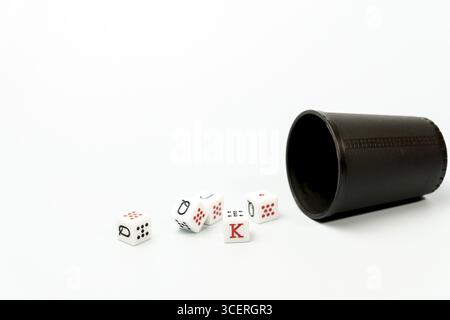 White poker dice with red and black markings rolling out of dark brown dice cup on white background Stock Photo