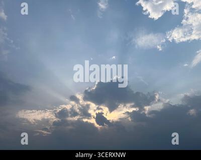 sunlight shining trough fluffy clouds in afternoon Stock Photo