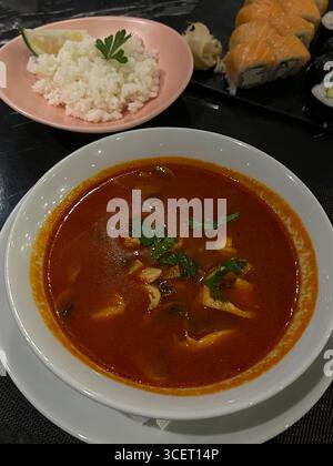 This photo shows a Japanese-style meal consisting of a red, spicy soup served in a white bowl with parsley garnish, placed on a white plate. To the si Stock Photo
