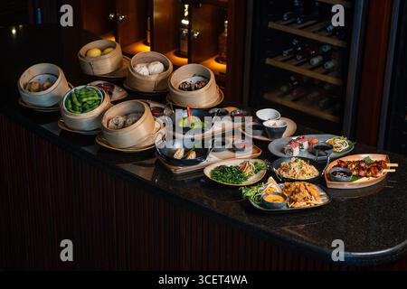 Assorted Chinese food set. Chinese noodles, fried rice, dumplings, dim sum, spring rolls. Famous Chinese cuisine dishes on a black background Stock Photo