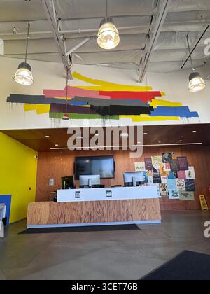 A modern reception area featuring a bold abstract mural with vibrant paint streaks in yellow, red, blue, pink, gray, green, and black. Stock Photo