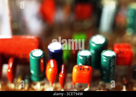 Close-up of electronic components on a circuit board. Various capacitors and resistors in different colors and sizes are visible. Focus on technology Stock Photo