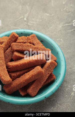 Tasty rye croutons on plate on grey concrete background. Top view Stock Photo